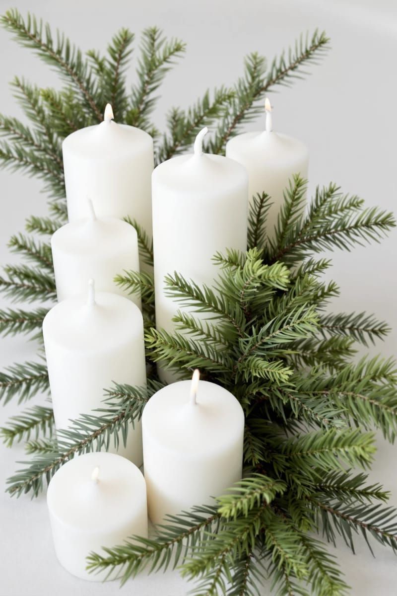 cluster of white pillar candles nestled in pine sprigs 1