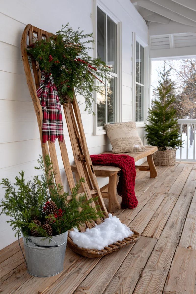 vintage sled decorated with greenery and plaid ribbon on the porch 1