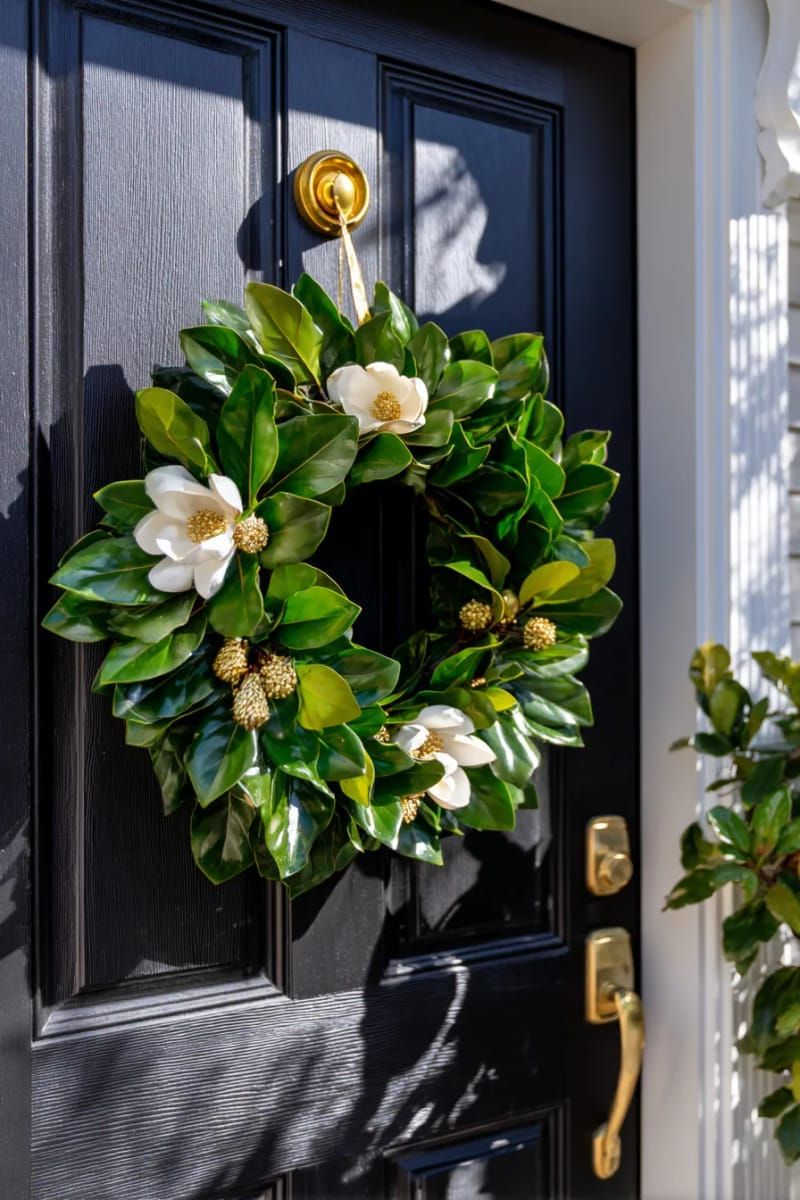 black door with simple magnolia wreath and golden accents for dramatic flair 1