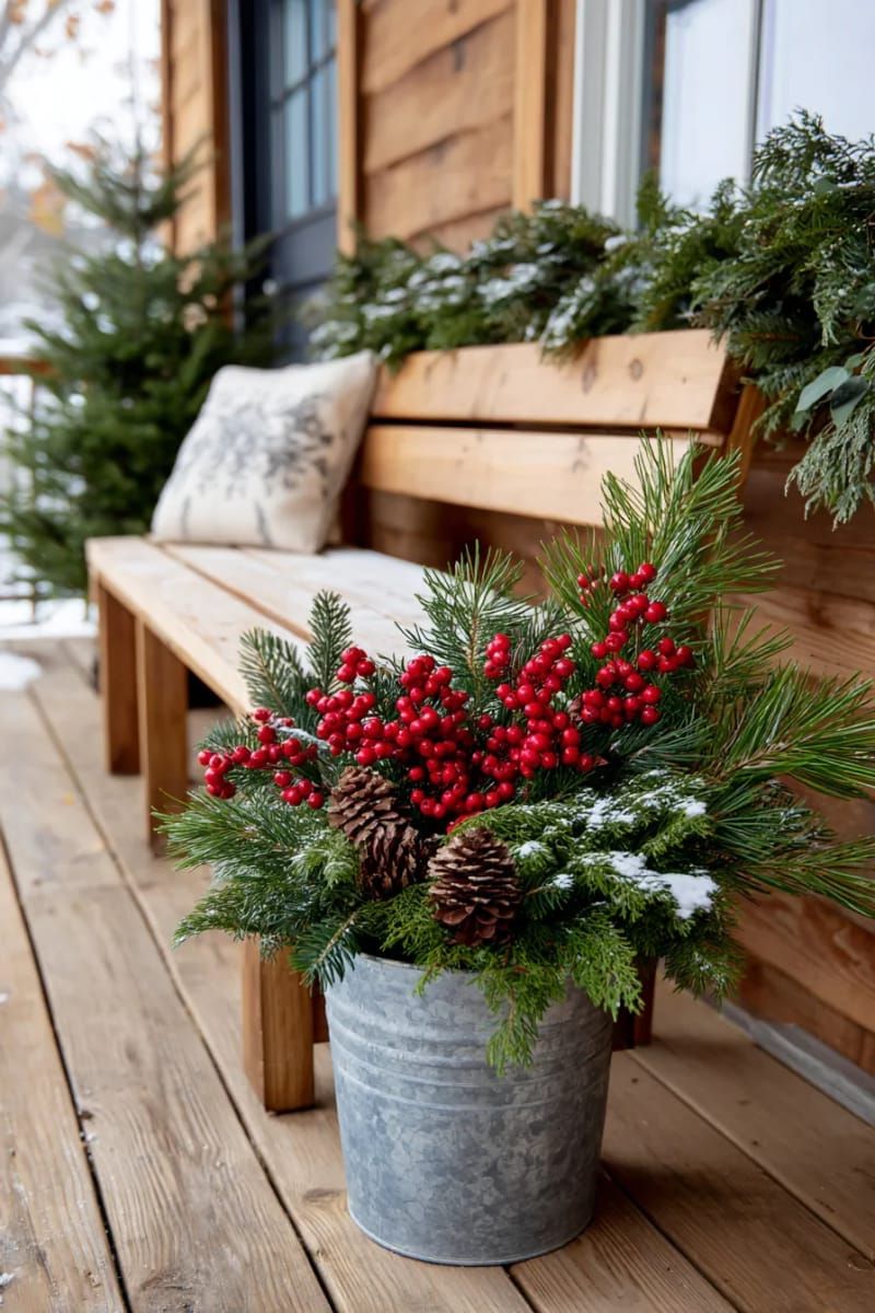 outdoor galvanized bucket overflowing with pine boughs and red berries 1