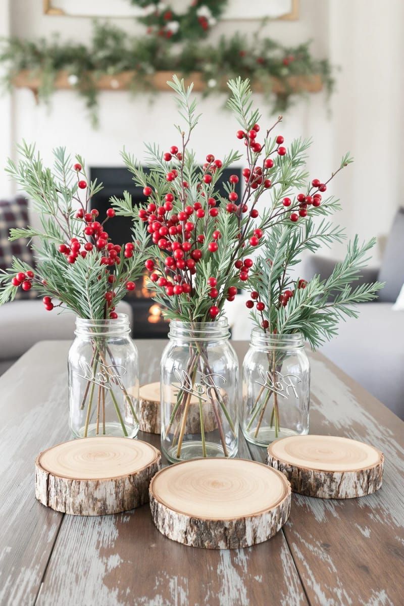 mason jar vases holding red berries, cedar sprigs, and wood slices 1