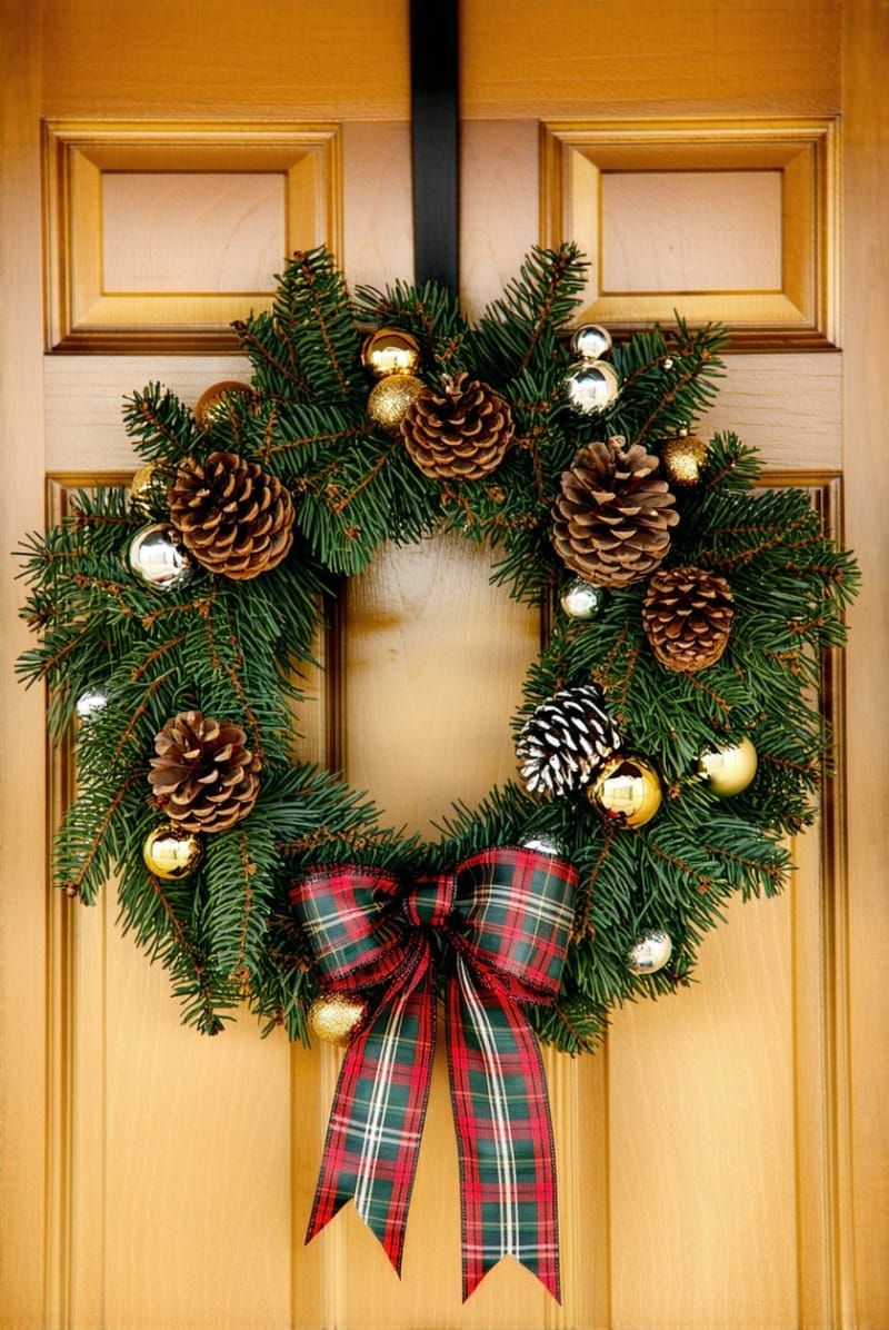 plaid and pinecone wreath with metallic baubles on a wooden front door 1