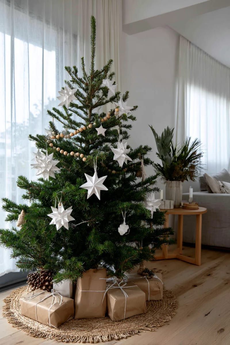 scandinavian style tree with white ornaments, paper stars, and natural wood garland 1