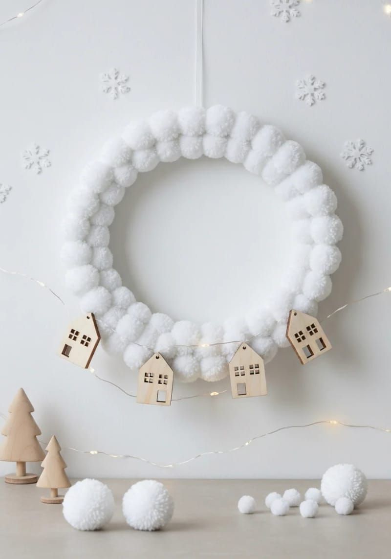 minimalist white wreath with pom-poms and tiny wooden houses 1